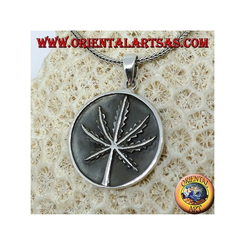 Medallón de plata con hoja de marihuana de bajo relieve.