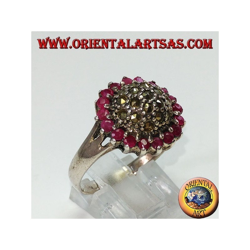 Anillo redondo de plata con un hemisferio de marcasita rodeado de 18 rubíes redondos.