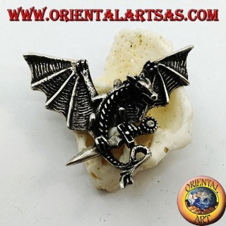 Pendentif dragon en argent avec ailes déployées et poignard entre les griffes