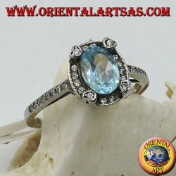 Silver ring with natural oval blue topaz set surrounded by zircons