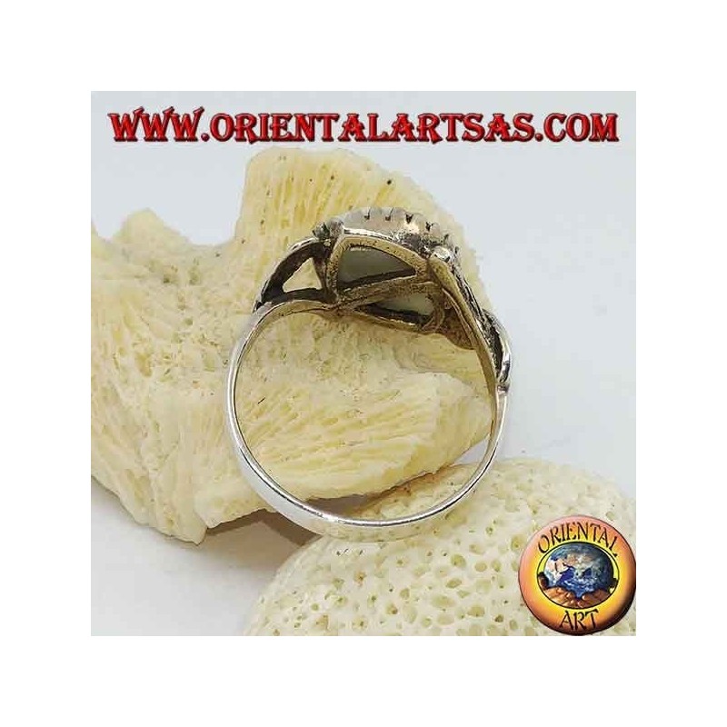 Silver ring with blue eye diagonally between two leaves