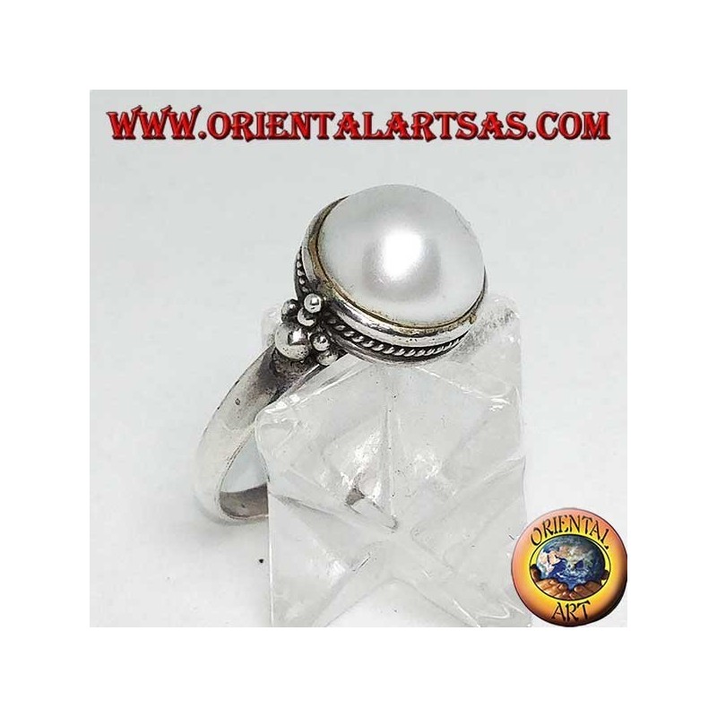 Silver ring with round pearl surrounded by braid decoration and balls on the sides