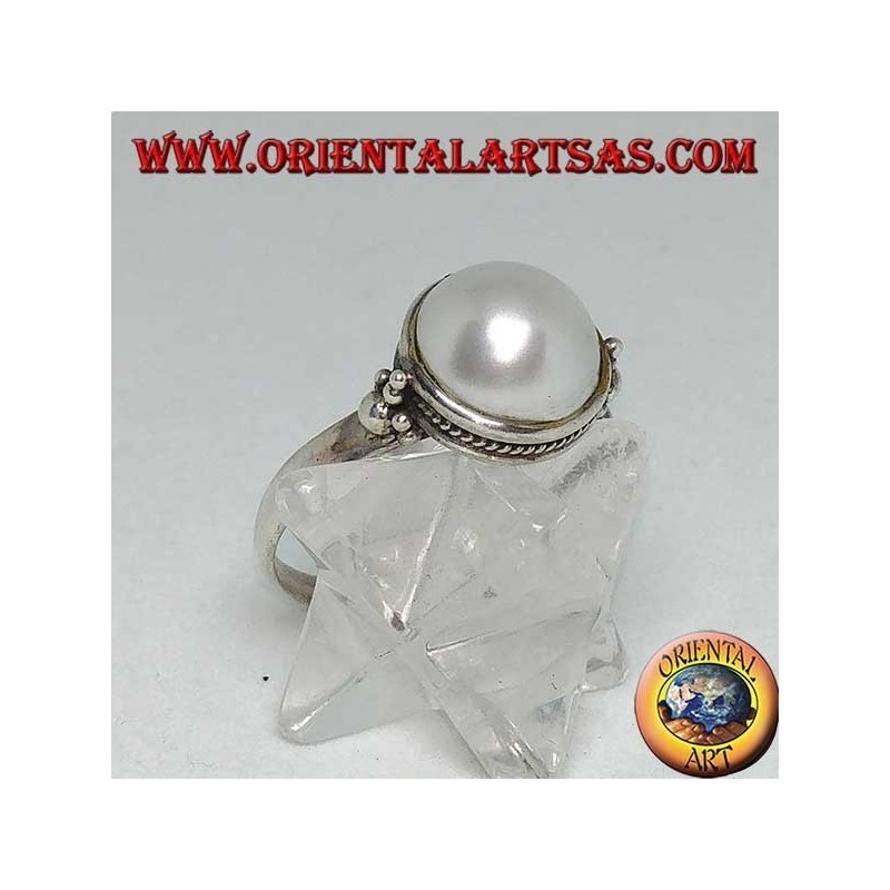 Anillo de plata con perla redonda rodeada de adornos trenzados y bolas a los lados.