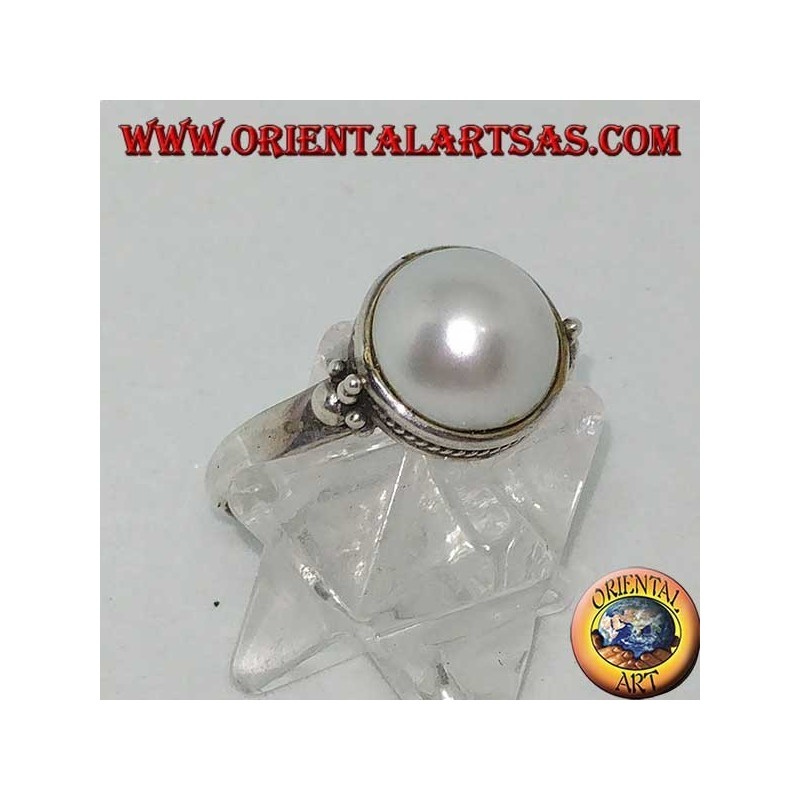 Silver ring with round pearl surrounded by braid decoration and balls on the sides