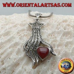 Colgante de plata, corazón de cornalina entre los dedos de una mano tachonada con marcasita