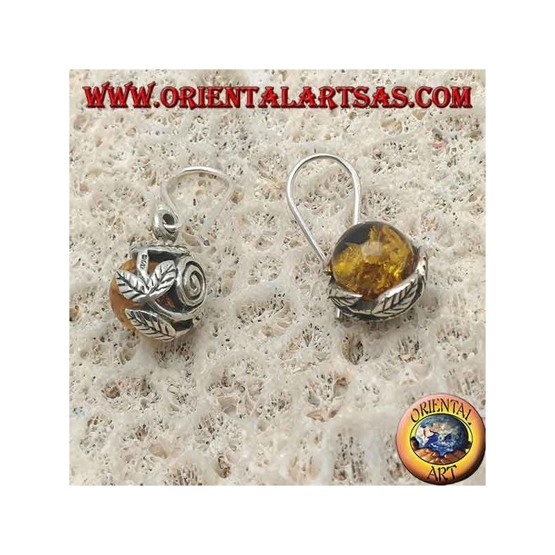Pendientes de plata con esfera de ámbar natural entre las hojas.