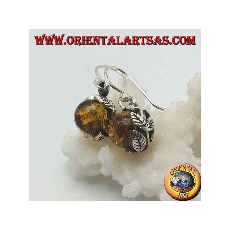 Pendientes de plata con esfera de ámbar natural entre las hojas.