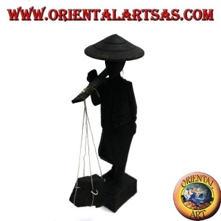 Sculpture of an ancient courier with straw hat and stick with ebony wood goods on the shoulder