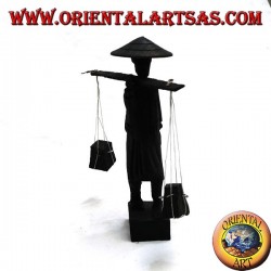 Escultura de un antiguo correo con sombrero de paja y palo con artículos de madera de ébano en el hombro.