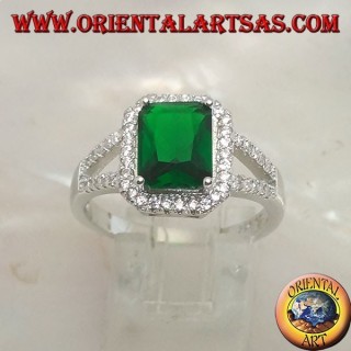 Anillo de plata con esmeralda sintética rectangular engastada rodeada de circonitas y dos líneas laterales.
