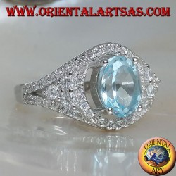 Anillo de plata con topacio azul natural ovalado en un marco con circonitas y tres rondas en los lados