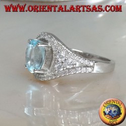 Anillo de plata con topacio azul natural ovalado en un marco con circonitas y tres rondas en los lados