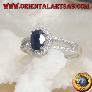 Anillo de plata con zafiro sintético ovalado, rodeado de circonitas y dos líneas laterales.