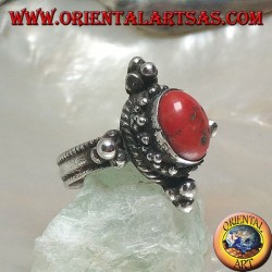 Anillo de plata con coral antiguo tibetano ovalado rodeado de puntos en un escenario nepalés