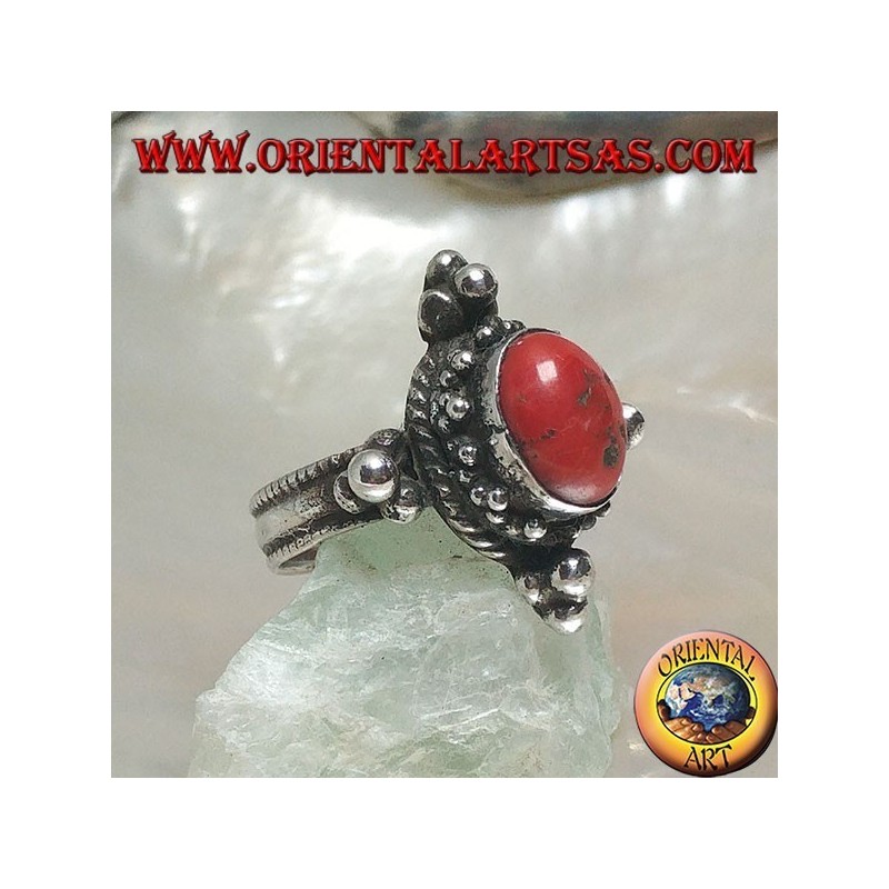 Anillo de plata con coral antiguo tibetano ovalado rodeado de puntos en un escenario nepalés