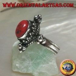 Anillo de plata con coral antiguo tibetano ovalado rodeado de puntos en un escenario nepalés