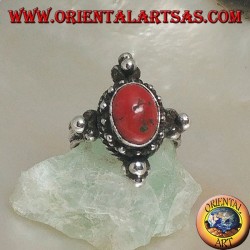 Anillo de plata con coral antiguo tibetano ovalado rodeado de puntos en un escenario nepalés