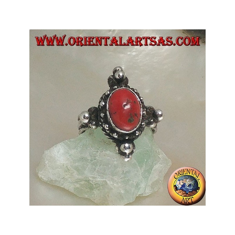 Anillo de plata con coral antiguo tibetano ovalado rodeado de puntos en un escenario nepalés