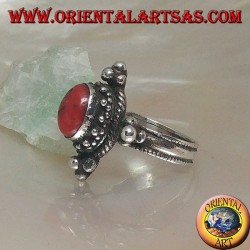 Anillo de plata con coral antiguo tibetano ovalado rodeado de puntos en un escenario nepalés