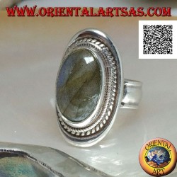 Silver ring with large oval labradorite in blue fluorescence cabochon surrounded by weaving on a smooth shield
