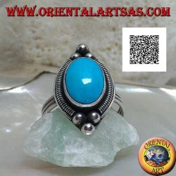 Silberring mit ovalem Cabochon-Türkis, umgeben von einer Verflechtung auf einem Teller und drei Kugeln oben und unten