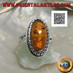 Silver ring with elongated oval amber surrounded by a serpentine in relief