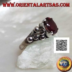 Silver ring with oval garnet set and spiral S between three balls on the sides