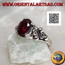 Silver ring with oval garnet set and spiral S between three balls on the sides