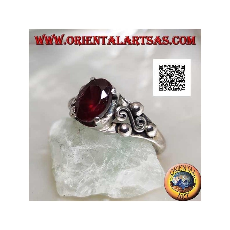 Silver ring with oval garnet set and spiral S between three balls on the sides