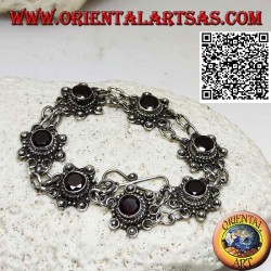 Silver bracelet of 7 flowers with central round faceted garnet joined by two chains