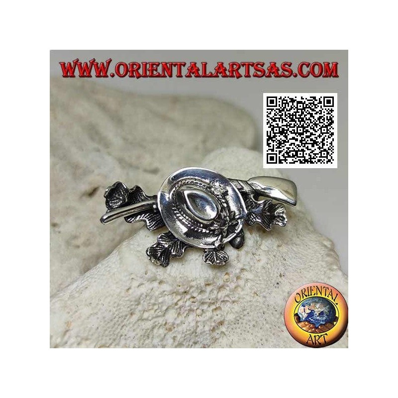 Broche de plata del cazador con sombrero y escopeta sobre alfombra de hiedra