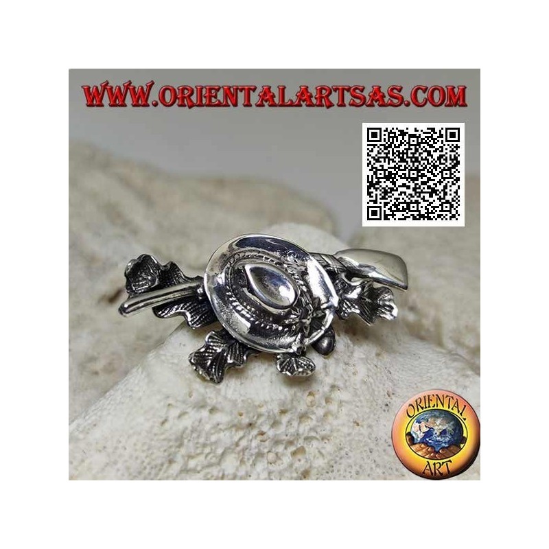 Silver brooch of the hunter with hat and shotgun on a carpet of ivy