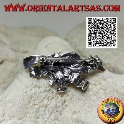 Silver brooch of the hunter with hat and shotgun on a carpet of ivy