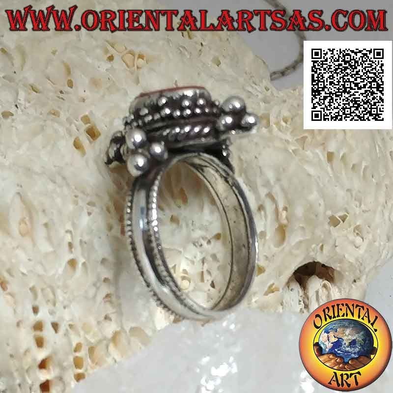 Anello in argento con corallo antico ovale contornato da tris di palline e intreccio e tris sui punti cardinali