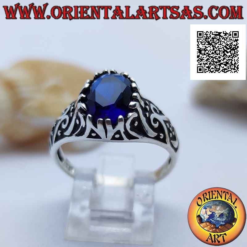 Silver ring with oval sapphire-colored zircon set on a frame decorated in bas-relief