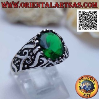 Silver ring with emerald-colored oval zircon set on a frame decorated in bas-relief