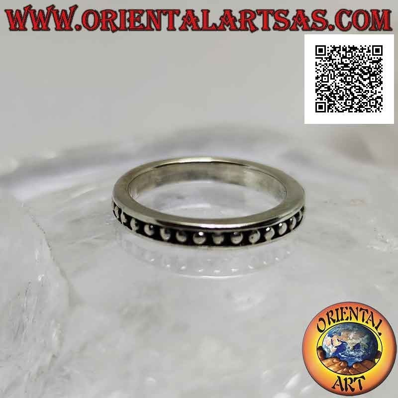 Silver band ring with small smooth spheres on a bas-relief background