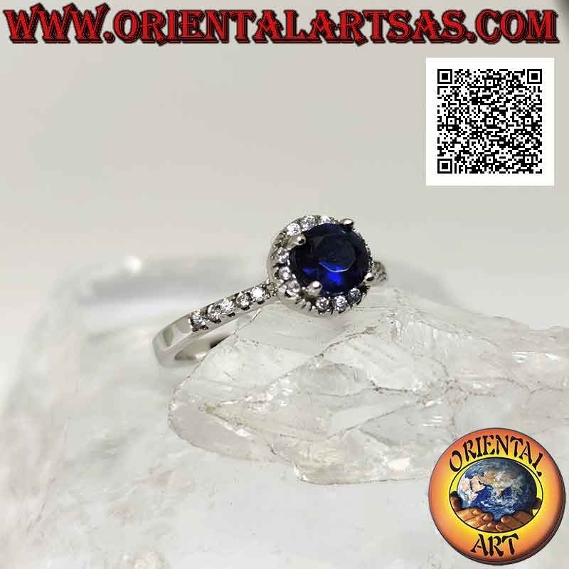 Silver ring with round synthetic sapphire set surrounded by white zircons and on the sides
