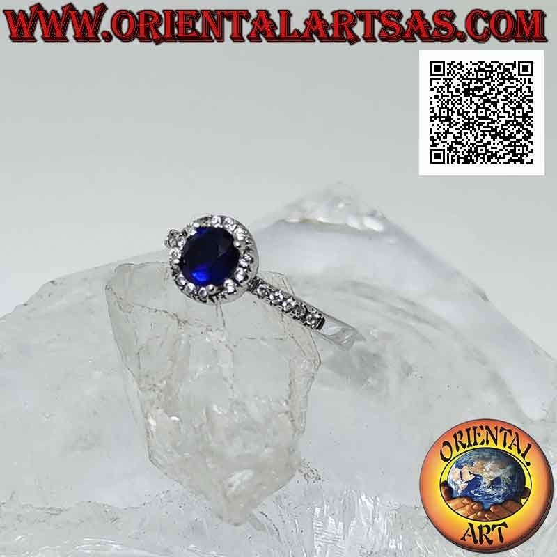 Anello in argento con zaffiro di sintesi tondo incastonato contornato da zirconi bianchi e sui lati