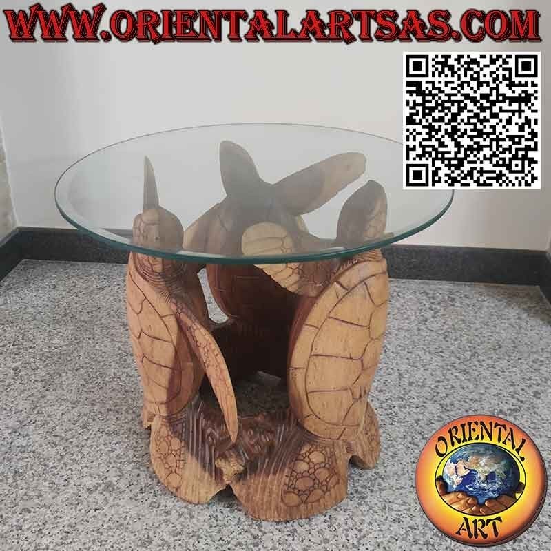 Mesa redonda con tres tortugas esculpidas y tapa de cristal tallado.