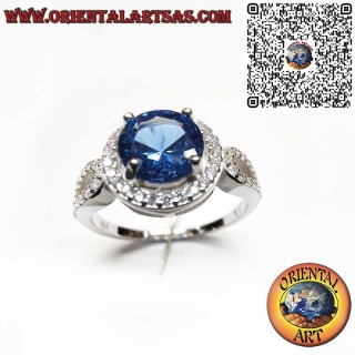 Bague en argent 925 ornée d'un saphir synthétique rond, serti dans un cadre et décoré de zircons sur les côtés.
